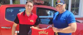 Funkcjonariusz CS PSP w stroju cywilnym oraz funkcjonariusz tureckiej straży pożarnej trzymający wspólnie T-Shirt tureckiej straży pożarnej