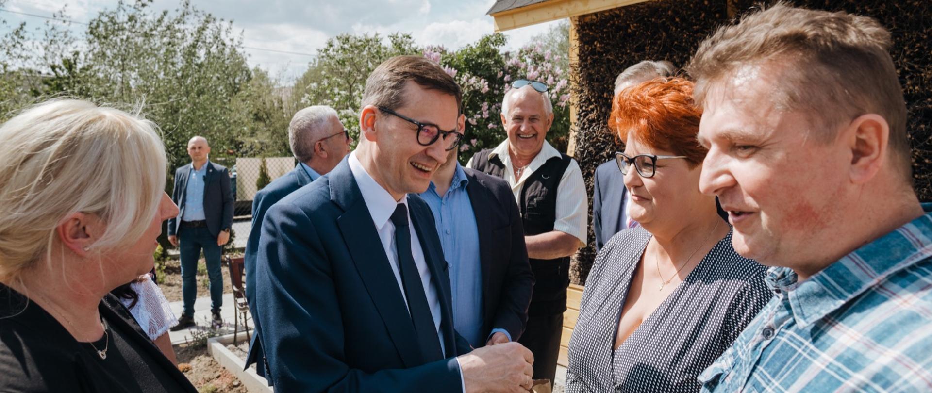 Premier rozmawia z seniorami na podwórku. 