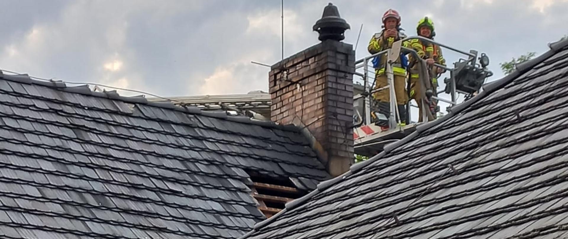 Strażacy w koszu drabiny przy spalonym kominie
