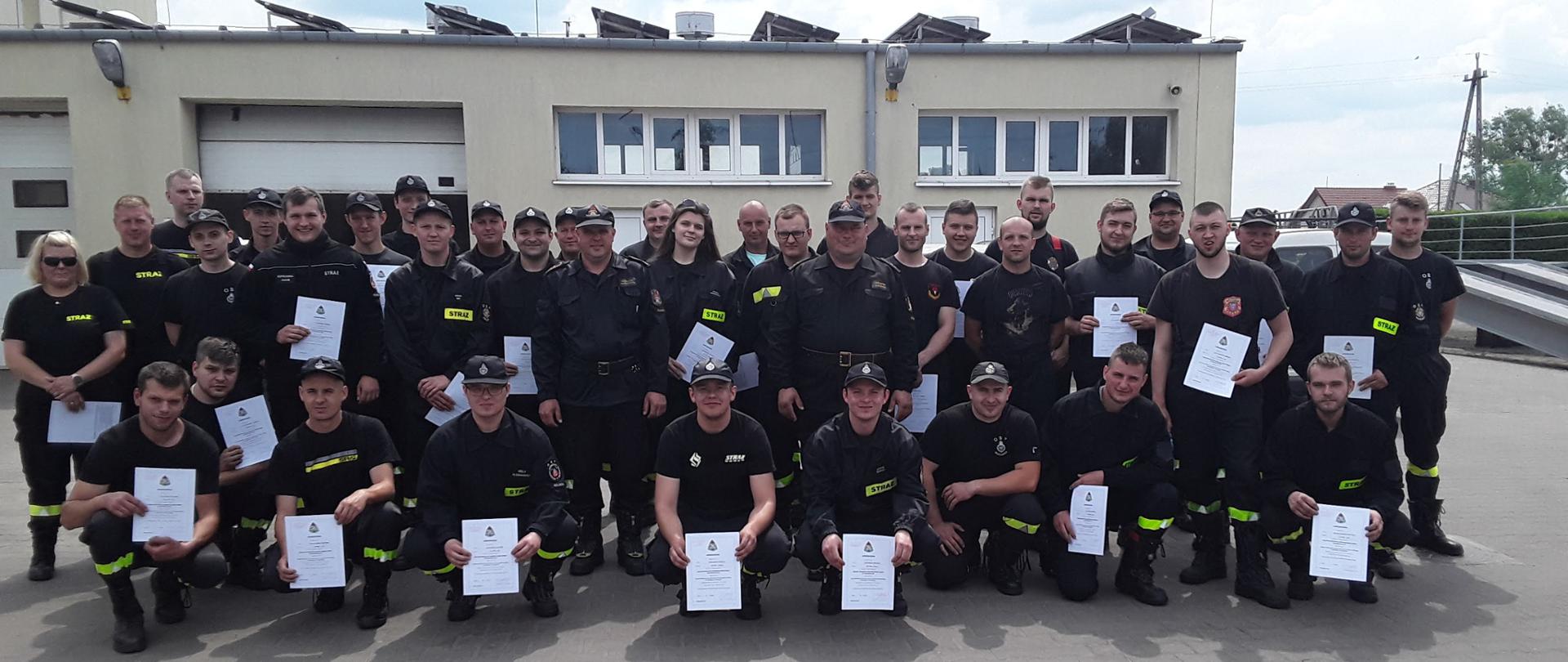 Zdjęcie przedstawia 40 uczestników Szkolenia Kierowców Konserwatorów sprzętu ratowniczego OSP na tle budynku Komendy Powiatowej PSP w Koluszkach