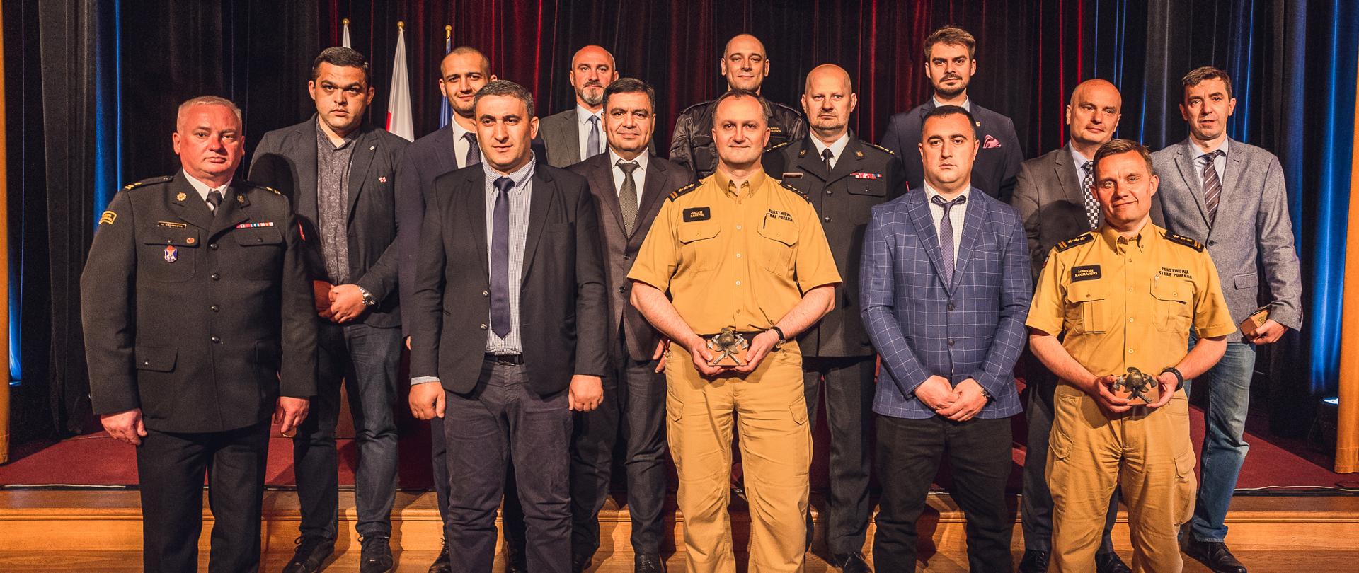 W trzech rzędach stoją przedstawiciele Służby Zarządzania Kryzysowego MSW Gruzji, przedstawiciele Komendy Głównej PSP, starosta powiatu żyrardowskiego, zastępca prezydenta miasta Żyrardowa oraz kierownictwo KP PSP w Żyrardowie