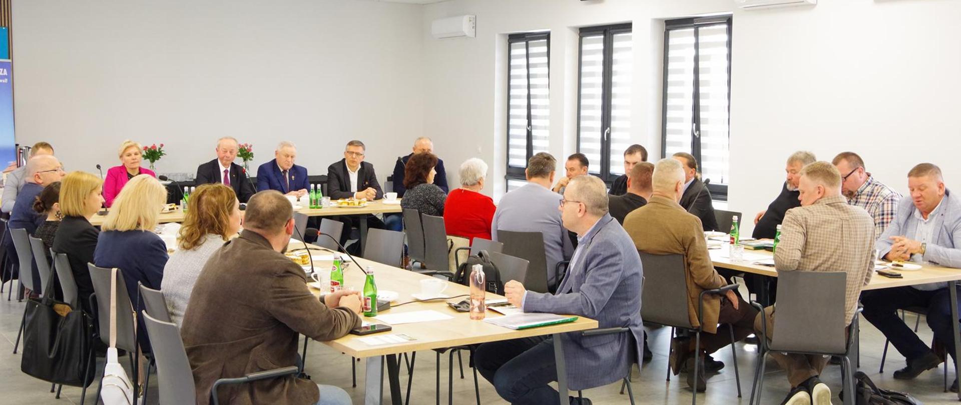 Uczestnicy posiedzenia siedzący na sali konferencyjnej przy stołach ułożonych w kształt podkowy