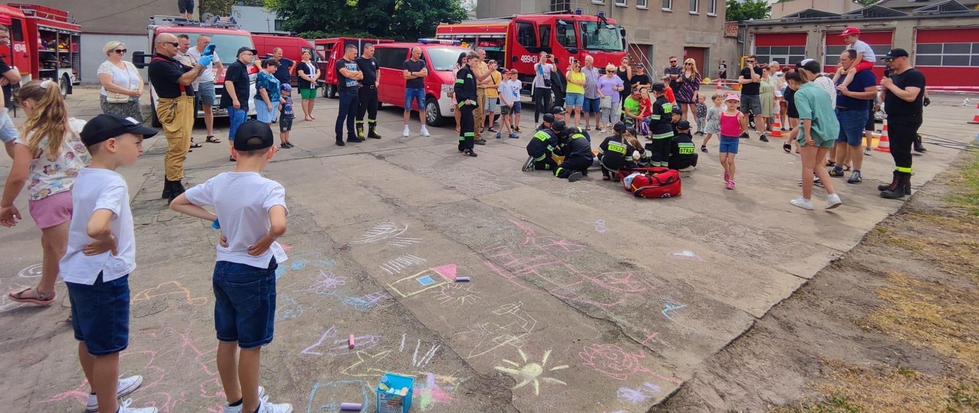 „Otwarta strażnica” w kościańskiej komendzie. Strażacy i Goście podczas akcji „Otwarta strażnica” w siedzibie kościańskiej komendy. Goście zwiedzają strażnicę, oglądają pojazdy, sprzęt i umundurowanie. Osoby biorą udział w pokazach sprzętu, ćwiczeniach z zakresu pierwszej pomocy. 