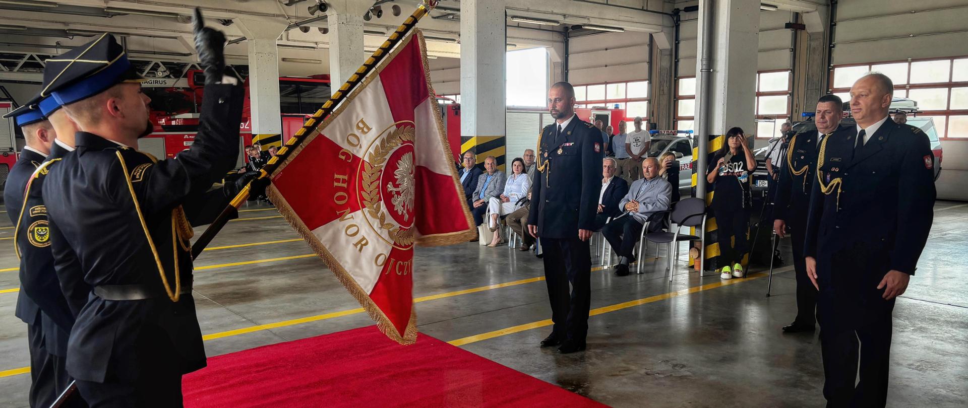 nowy i zdający obowiązek komendanta stoją przed sztandarem PSP w Wałbrzychu, w tle przedstawiciele władz miasta i powiatu