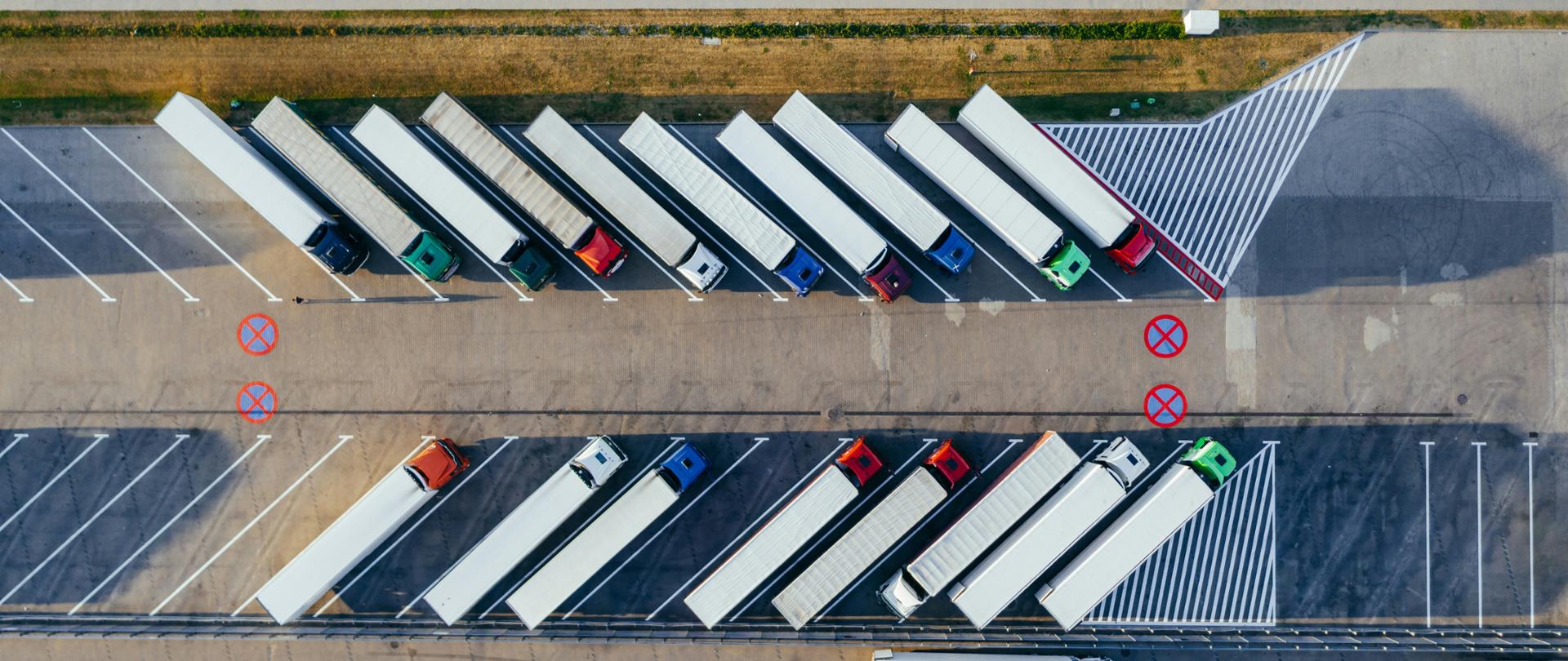 Kilkanaście ciężarówek stoi na parkingu.