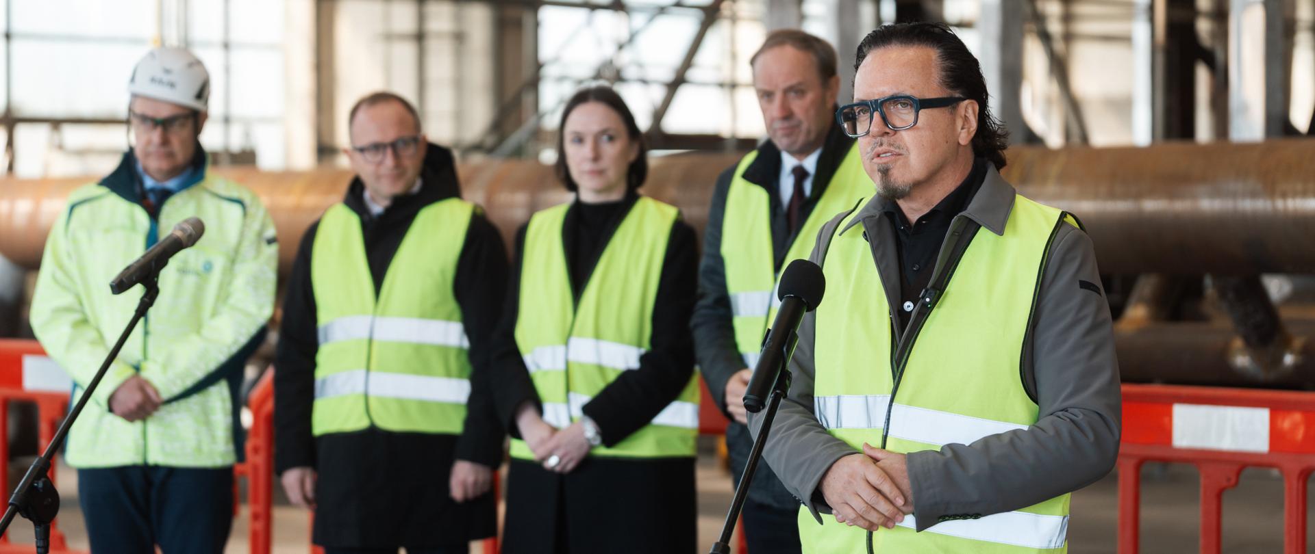 Minister Wojciech Balczun przemawia przez mikrofon. Z tyłu stoi wiceminister Eliza Zeidler. 