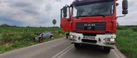 Na zdjęciu widoczny pojazd Straży Pożarnej. Samochód, który uległ wypadkowi znajduje się w rowie.