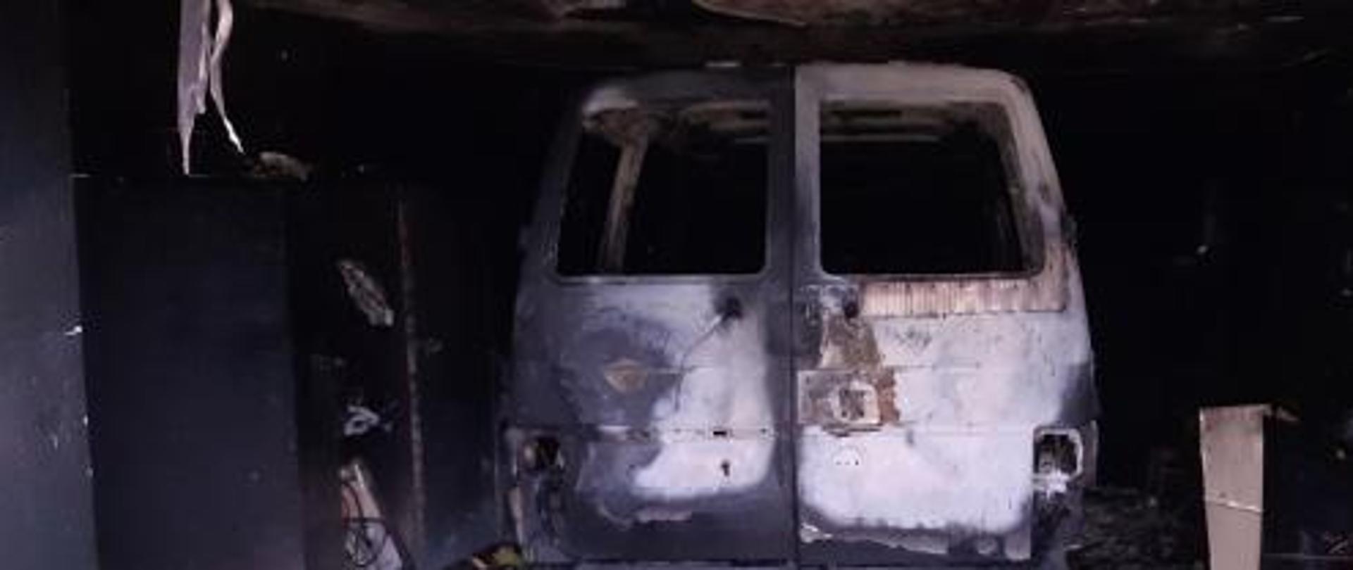 Widoczny garaż po pożarze. Wewnątrz znajduje się spalone auto. Wnętrze garażu spalone.