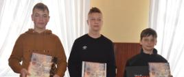 OTWP w Sobiałkowie. Świetlica wiejska w Sobiałkowie. Zwycięzcy w średniej grupie wiekowej pozują do wspólnego zdjęcia. Trzech chłopaków trzyma w rękach dyplomy oraz niebieskie torby z upominkami.