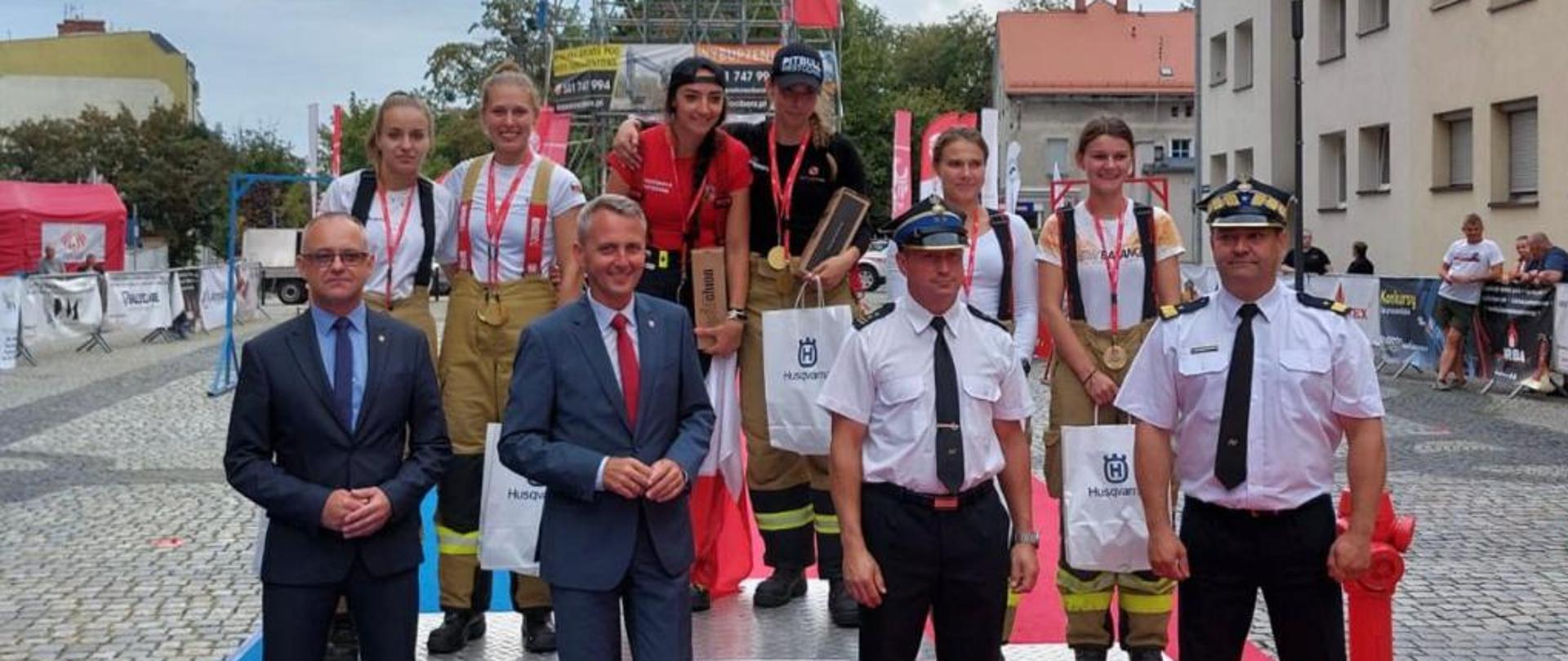 Na zdjęciu zawodniczki na podium z nagrodami przed nimi zaproszeni goście i organizatorzy w tym funkcjonariusze PSP 
