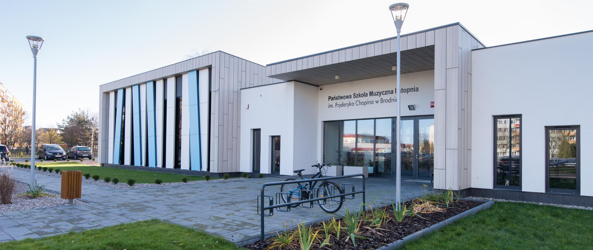 Zdjęcie budynku naszej szkoły, od strony ulicy Wyspiańskiego, trawnik i zagospodarowanie przed wejściem głównym