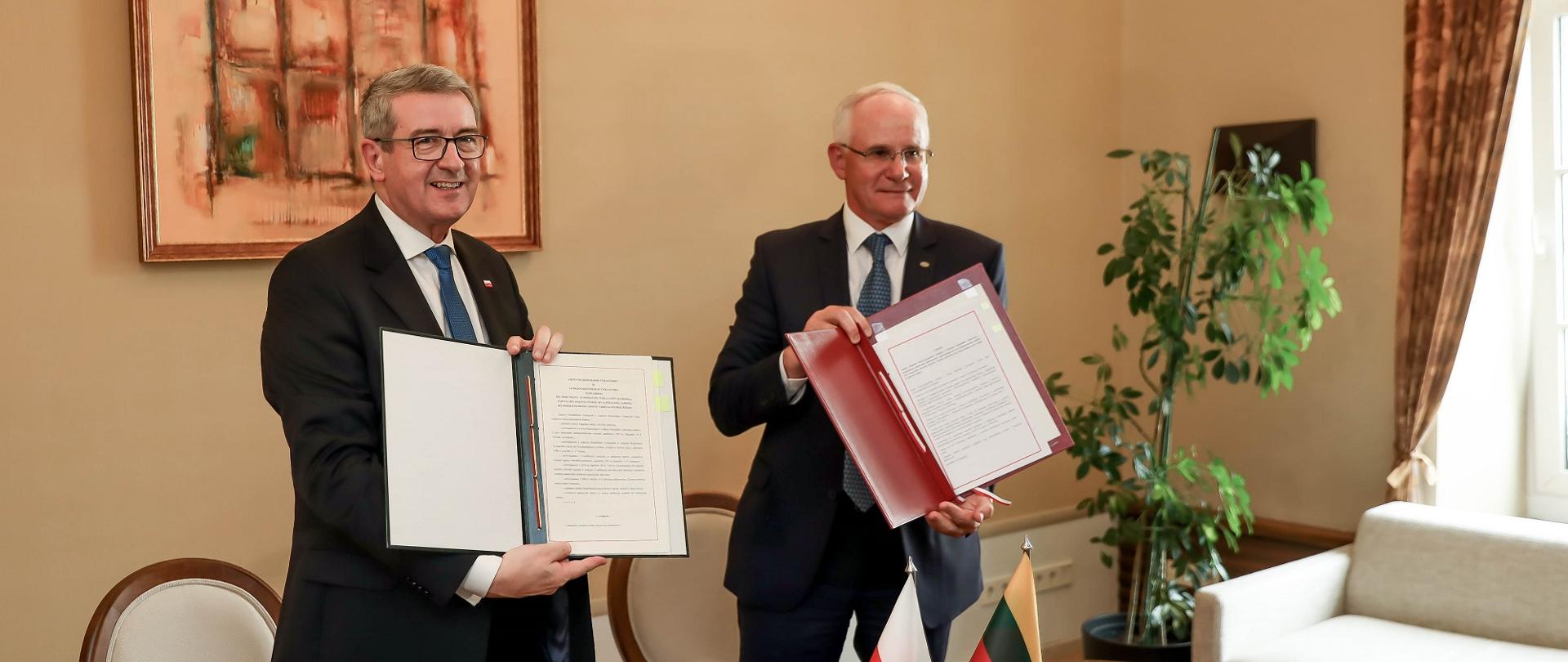 Ministrowie prezentują podpisane egzemplarze umów.