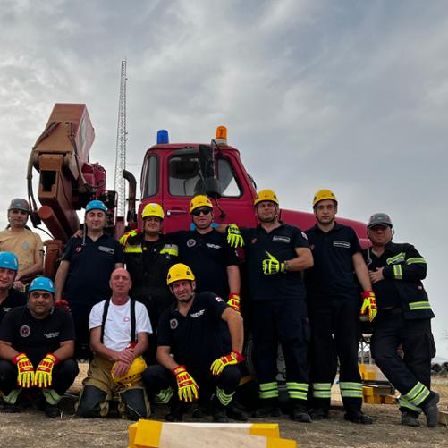 Grupa strażaków stoi przed specjalistycznym samochodem gaśniczym