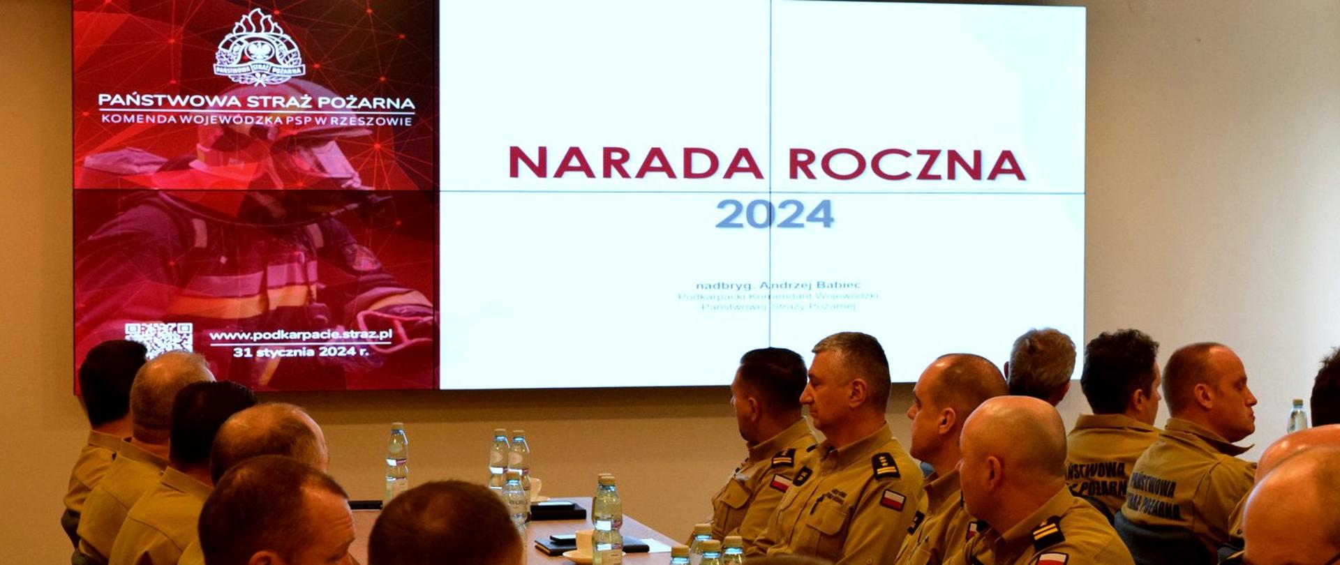 Zdjęcie zrobione w Sali podczas narady. Na zdjęciu uczestnicy narady służbowej, wśród nich osoby cywilne i oficerowie Państwowej Straży Pożarnej.