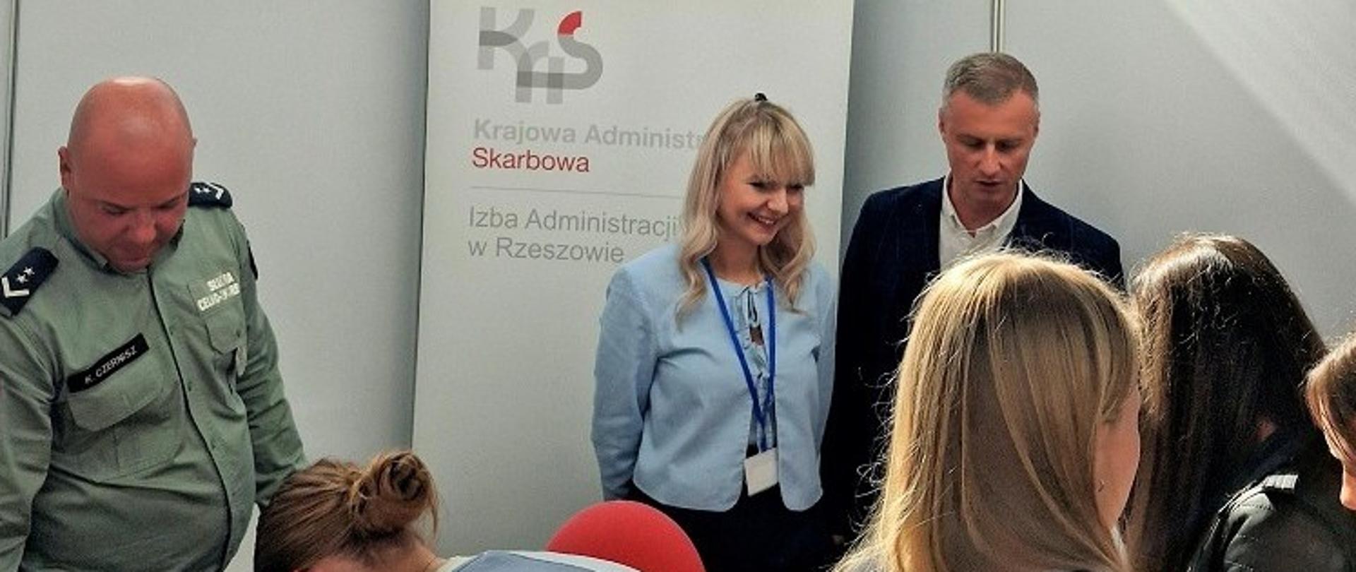 Przedstawiciele podkarpackiej KAS stoją przy stanowisku. Przed nimi są uczestnicy targów.