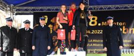 Zdjęcie przedstawia zawodników na podium z nagrodami.