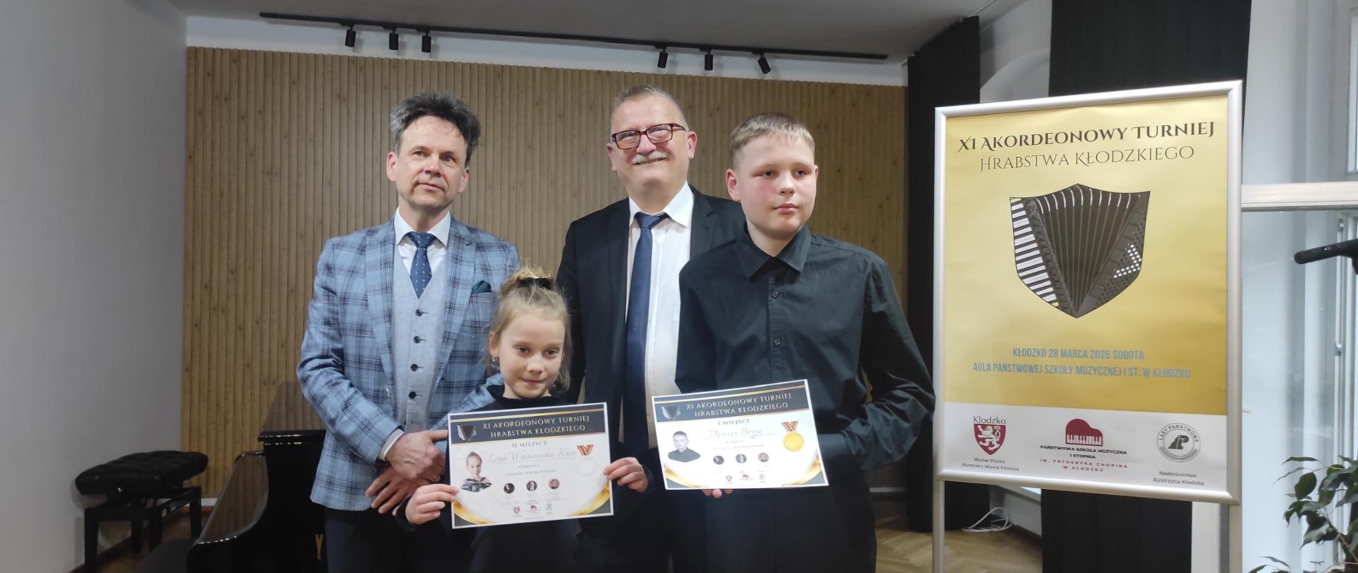 zdjęcie przedstawia laureatów konkursu wraz z jurorami na tle plakatu XI Akordeonowego Turnieju Hrabstwa Kłodzkiego