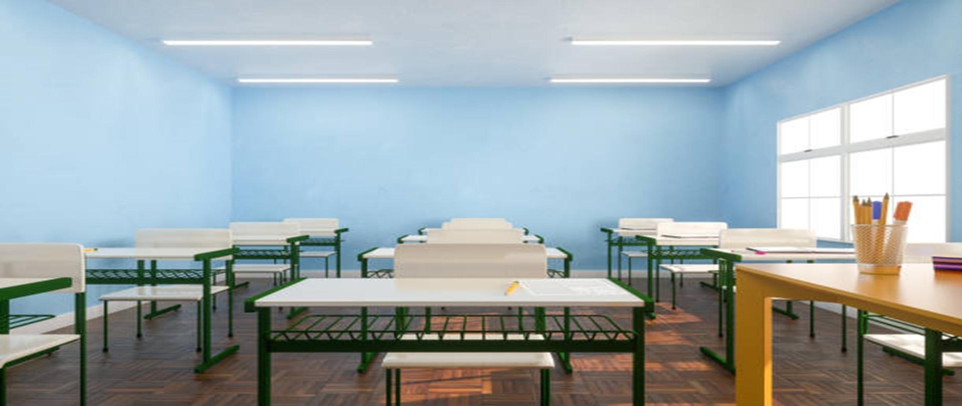 Białe stoły i krzesła ustawione w rzędach przy oknie w oświetlonej słońcem klasie z niebieskimi ścianami. 