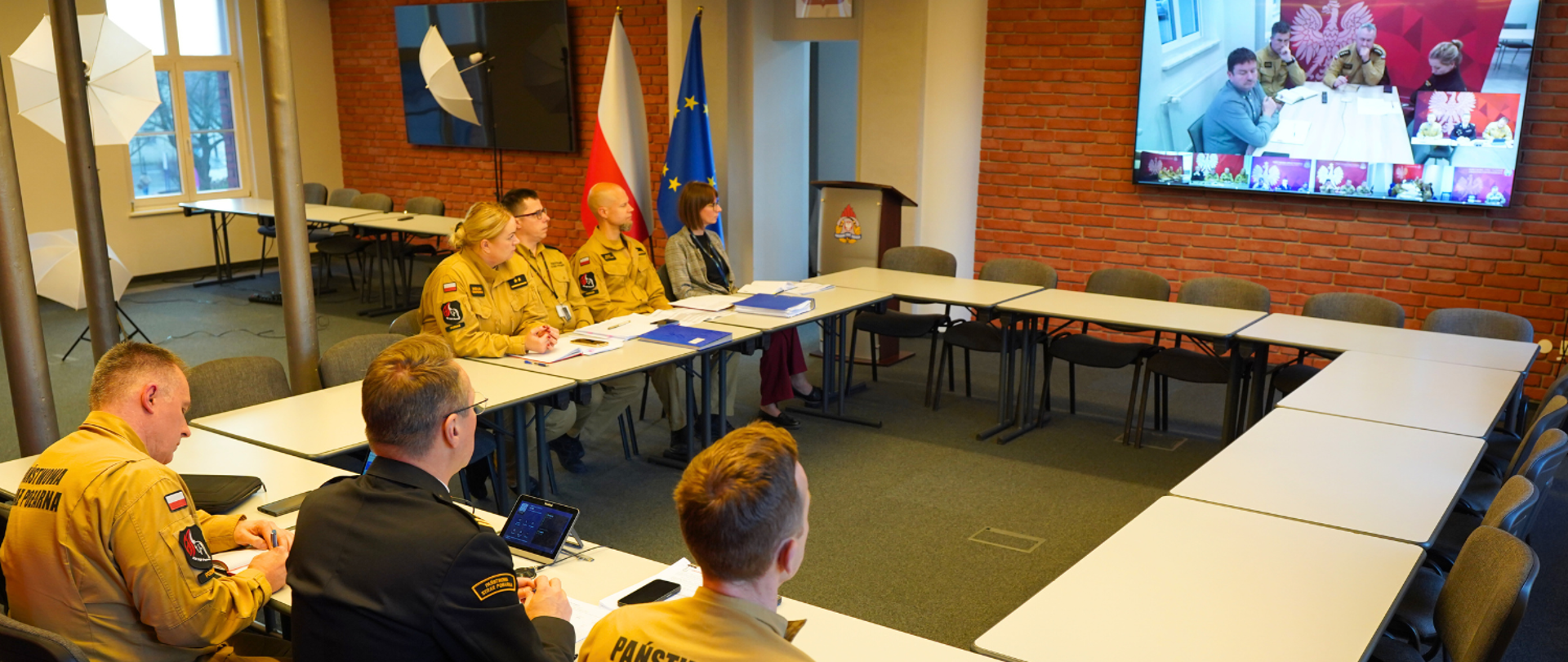 Panowie komendanci prowadzą spotkanie wideokonferencyjne, siedząc przy stołach w sali komendy wojewódzkiej