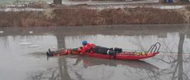 Strażak na saniach lodowych podejmujący osobę poszkodowaną z przerębla.