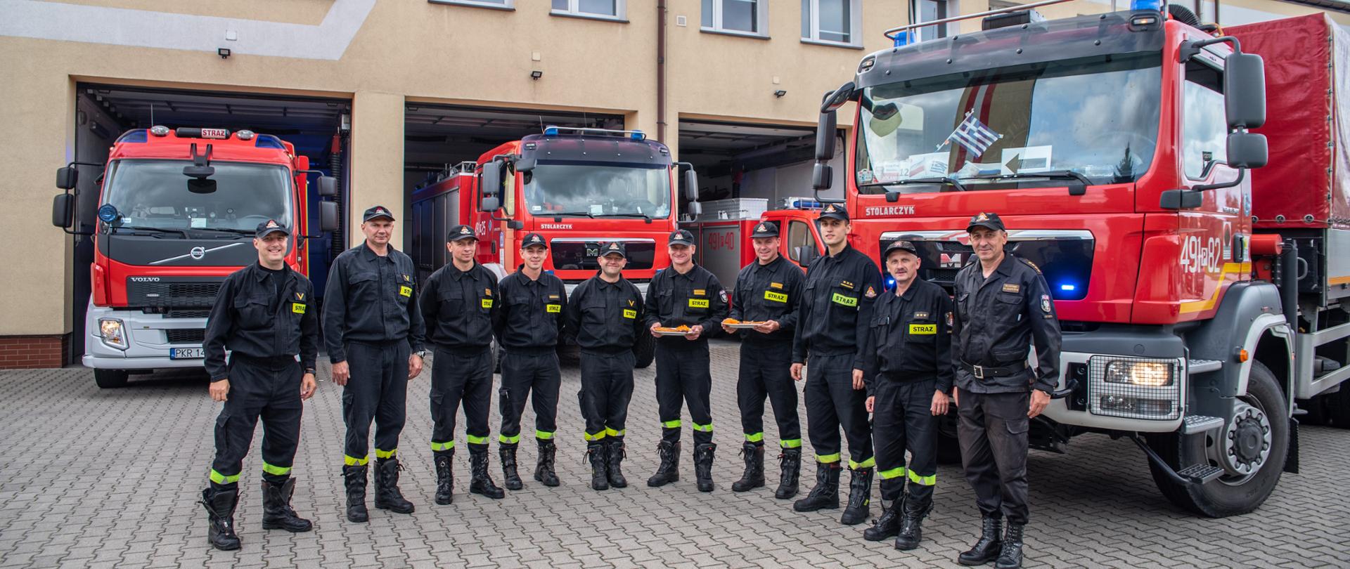 Przed pojazdami krotoszyńskiej komendy stoją w szyku strażacy ze zmiany służbowej,ratownicy, którzy powrócili z misji oraz d-ca jednostki. Pamiątkowe zdjęcie z powitania strażaków. 