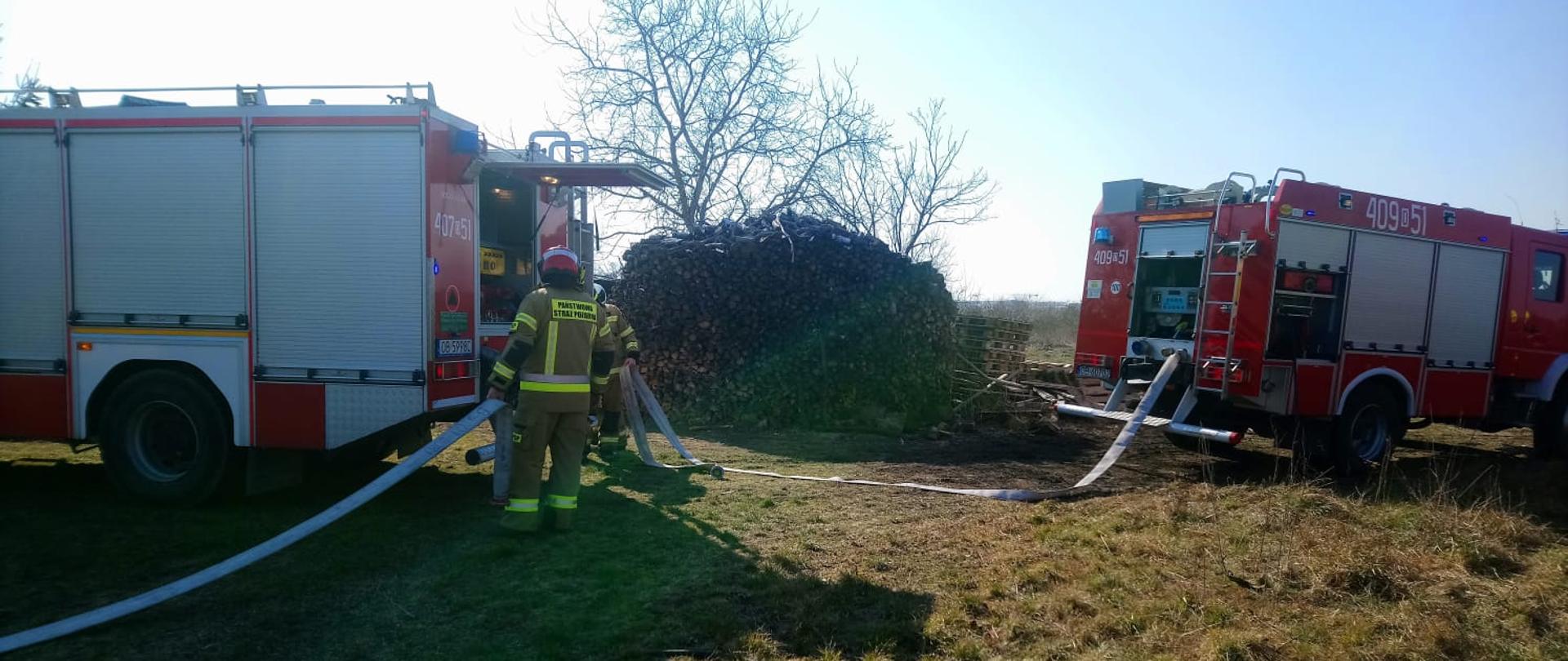 Podsumowanie zdarzeń w dniach 7.03 - 13.03.2022 r.- zdjęcie przedstawia strażaków na tle 2 samochodów gaśniczych, którzy biorą udział w działaniach gaśniczych