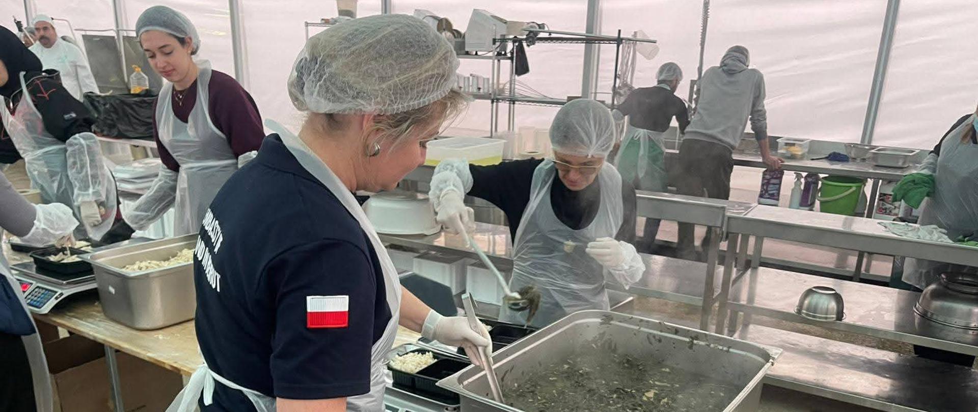 Women in aprons and caps pack food into containers 
