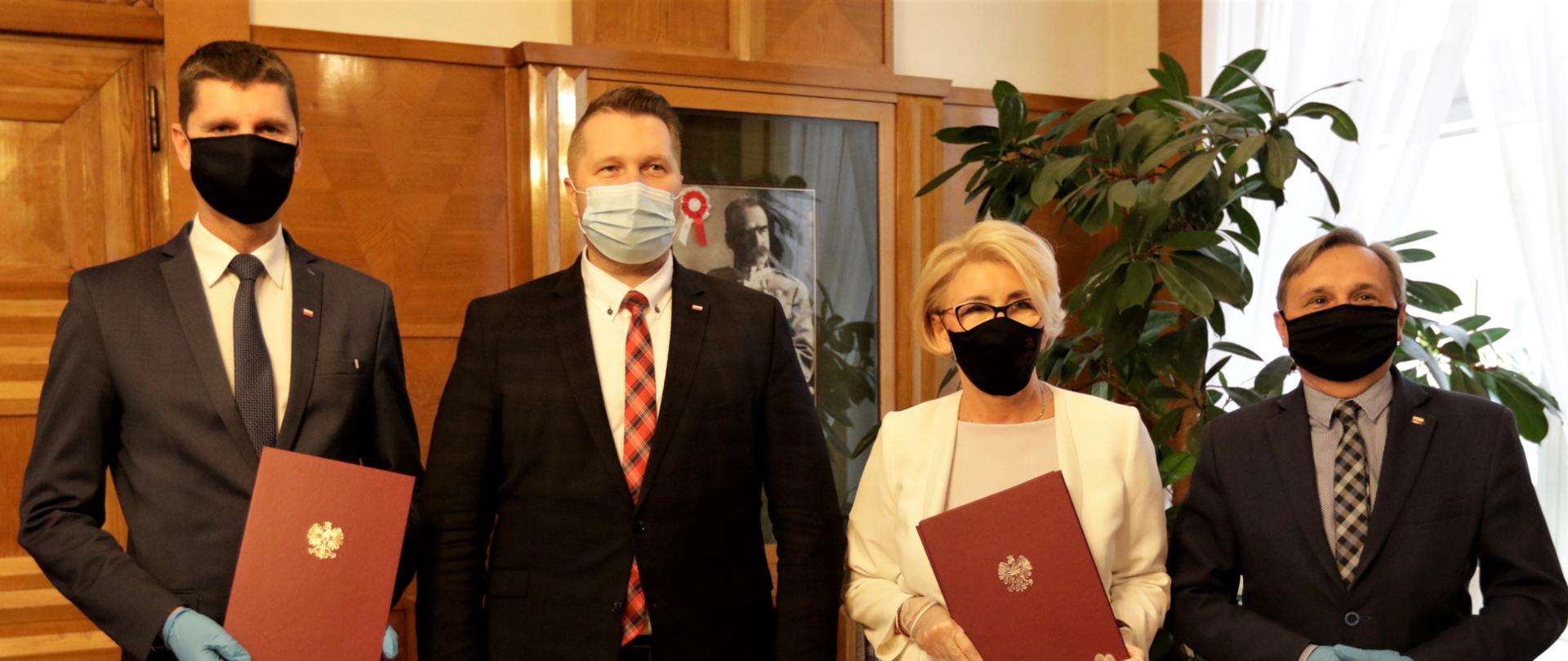 Na zdjęciu kierownictwo MEN. Od lewej sekretarz stanu w MEN Dariusz Piontkowski, Minister Edukacji i Nauki Przemysław Czarnek, sekretarz stanu w MEN, pełnomocnik rządu do spraw do spraw wspierania wychowawczej funkcji szkoły i placówki, edukacji włączającej oraz kształcenia zawodowego Marzena Machałek oraz podsekretarz stanu w MEN Maciej Kopeć. Wiceministrowie Dariusz Piontkowski oraz Marzena Machałek trzymają w rękach akty powołania. 