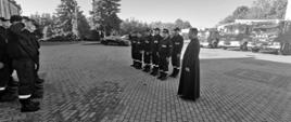 Zdjęcie przedstawia straszaków JRG Brodnica oddających hołd strażakowi Komendy Głównej PSP, który 6 sierpnia zginął w wypadku podczas służby. Na pierwszym planie ks. Mariusz Stasiak Kapelan Kujawsko-Pomorskich strażaków. W tle pojazdy ratowniczo - gaśnicze Komendy