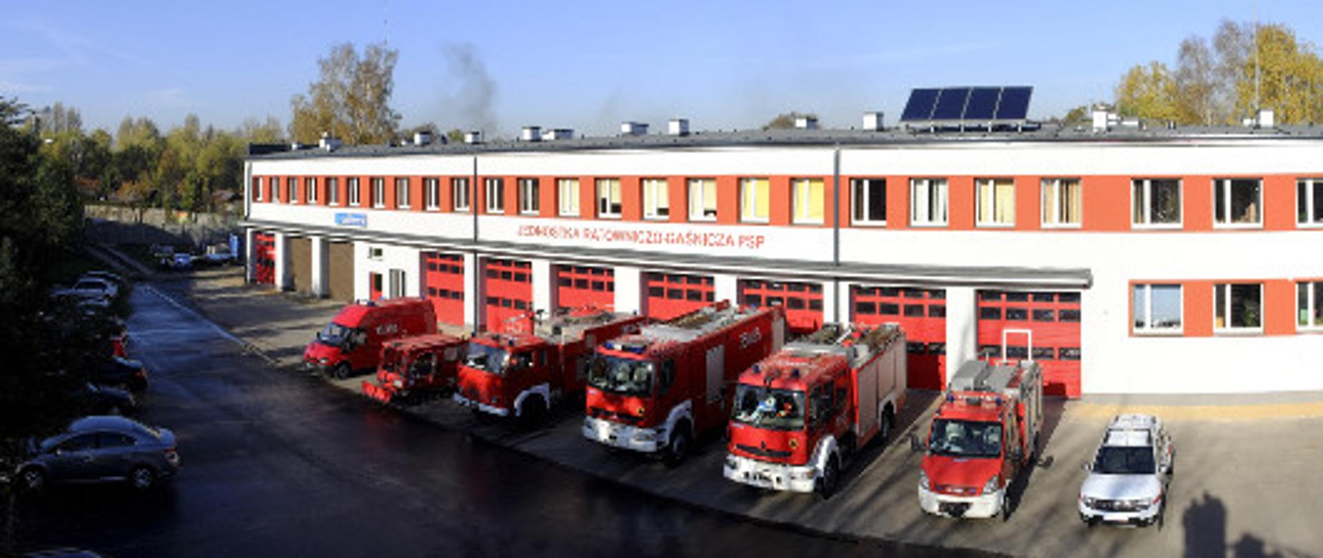 Zdjęcie z wysokości przedstawiające widok na obiekt Jednostki Ratowniczo Gaśniczej nr 1. Przed obiektem znajdują się pojazdy będące na wyposażeniu Jednostki. 