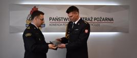Komendant Powiatowy Państwowej Straży Pożarnej w Ostródzie, starszy brygadier Tomasz Ostrowski wręcza pamiątkową tabliczkę starszemu kapitanowi Bogdanowi Grzymowiczowi.