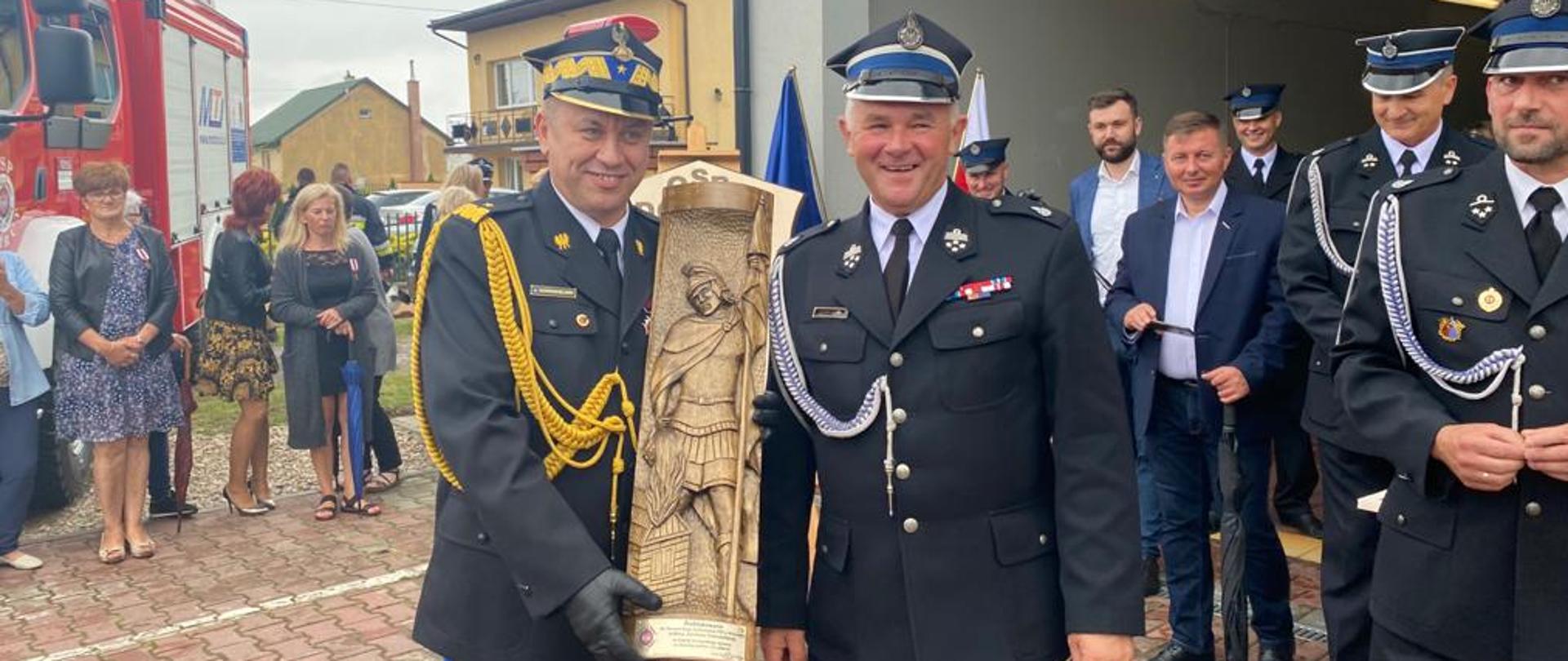 Fotografia przedstawiająca wręczenie figurki św. Floriana przez Prezesa OSP Dobrut dla Mazowieckiego Komendanta Wojewódzkiego