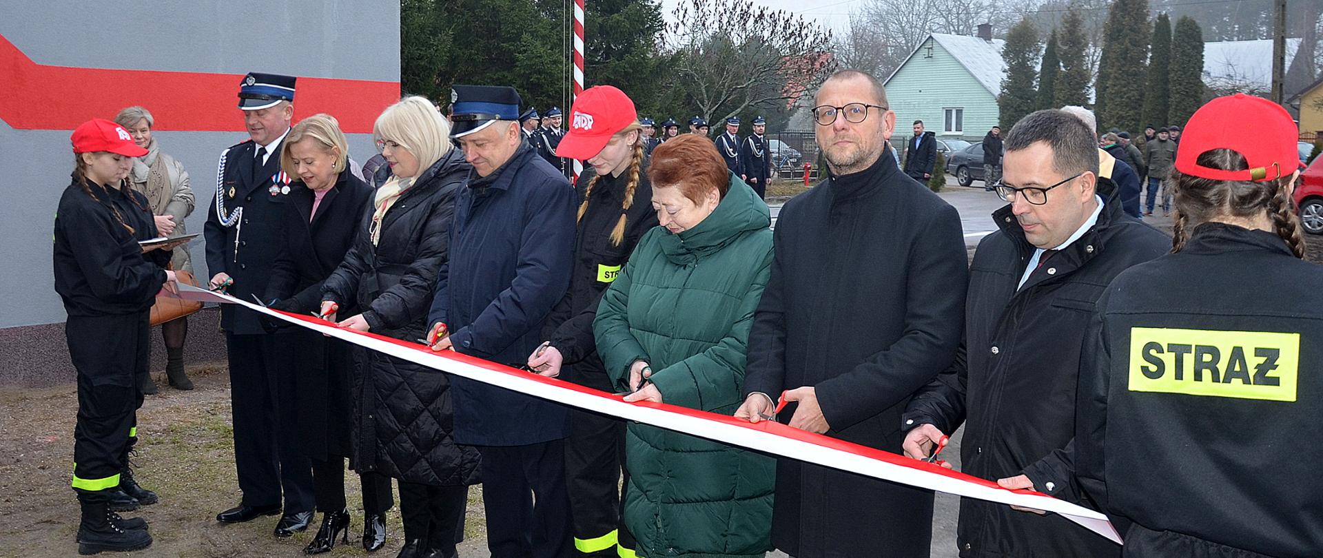 Na zdjęciu grupa ludzi przecina biało czerwoną wstęgę 