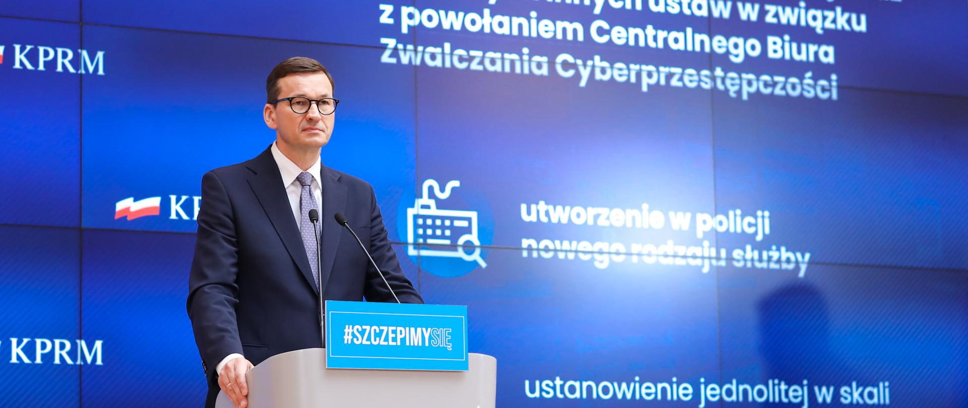 Premier Mateusz Morawiecki stoi przy mównicy podczas konferencji prasowej na temat cyberbezpieczeństwa w Polsce