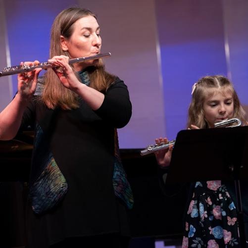 Gafika przedstawia osoby grające na flecie poprzecznym