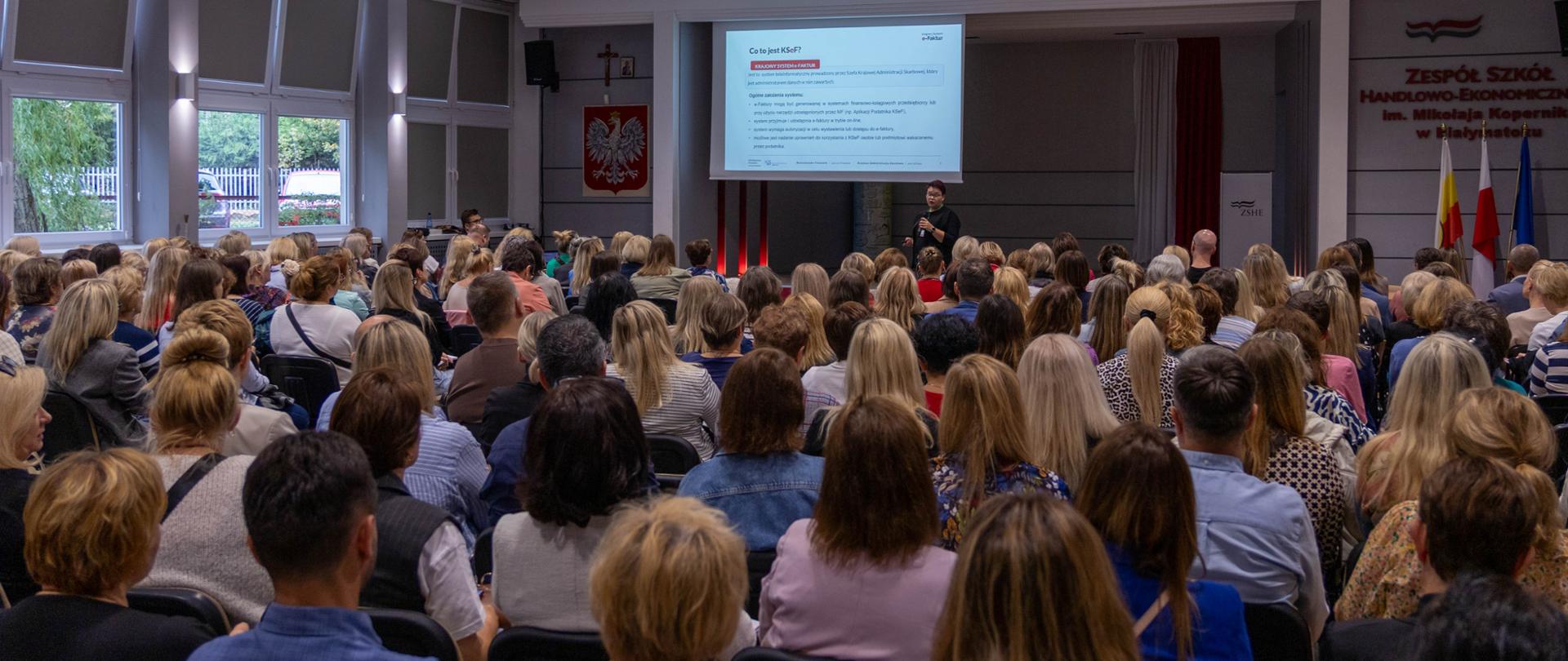 Wiele ludzi zebranych w auli podczas prezentacji