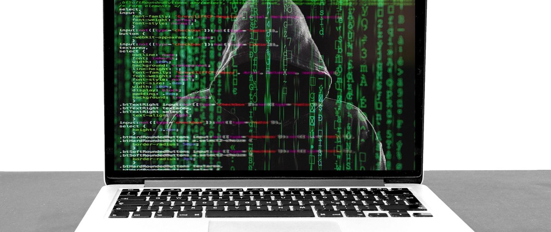 laptop, na ekranie postać osoby w kapturze