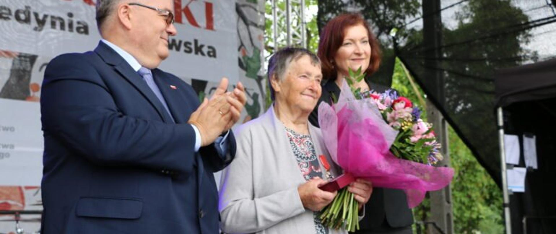 Od lewej sekretarz stanu w Kancelarii Prezydenta RP minister Andrzej Dera, Władysława Prucnal trzymająca kwiaty oraz wojewoda podkarpacki Ewa Leniart