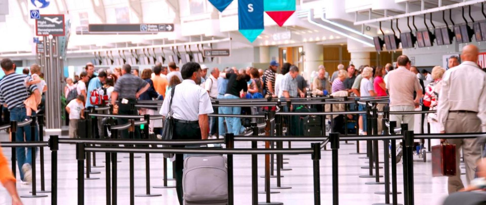 Bardzo dużo podróżujących z walizkami i torbami podróżnymi na lotnisku
