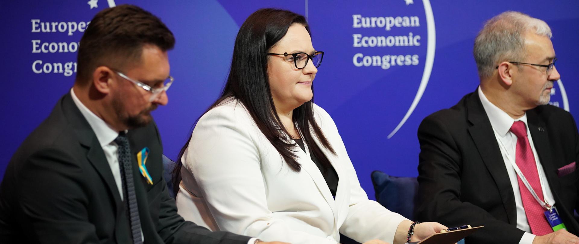 Na zdjęciu od prawej: prezydent Katowic Marcin Krupa, wiceminister funduszy i polityki regionalnej Małgorzata Jarosińska-Jedynak, wiceprezes zarządu Banku Pekao S.A. siedzący na fotelach w trakcie debaty. W tle ścianka Europejskiego Kongresu Gospodarczego. 