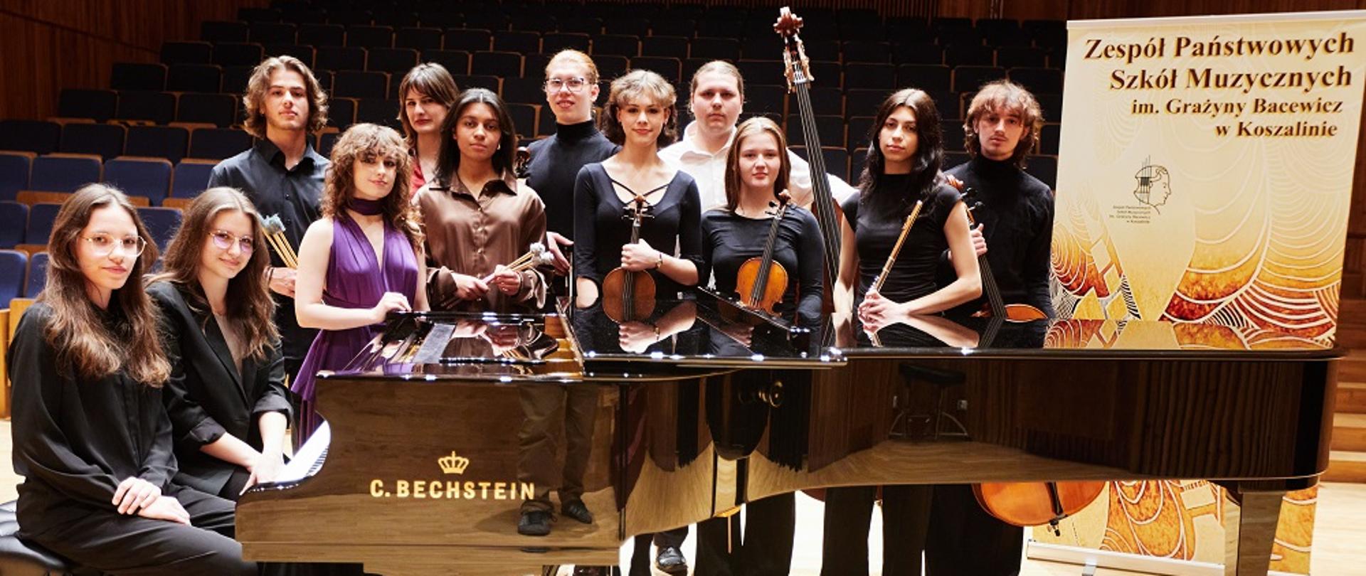 Uczniowie ZPSM przy fortepianie, na tle sali w Filharmonii Koszalińskiej