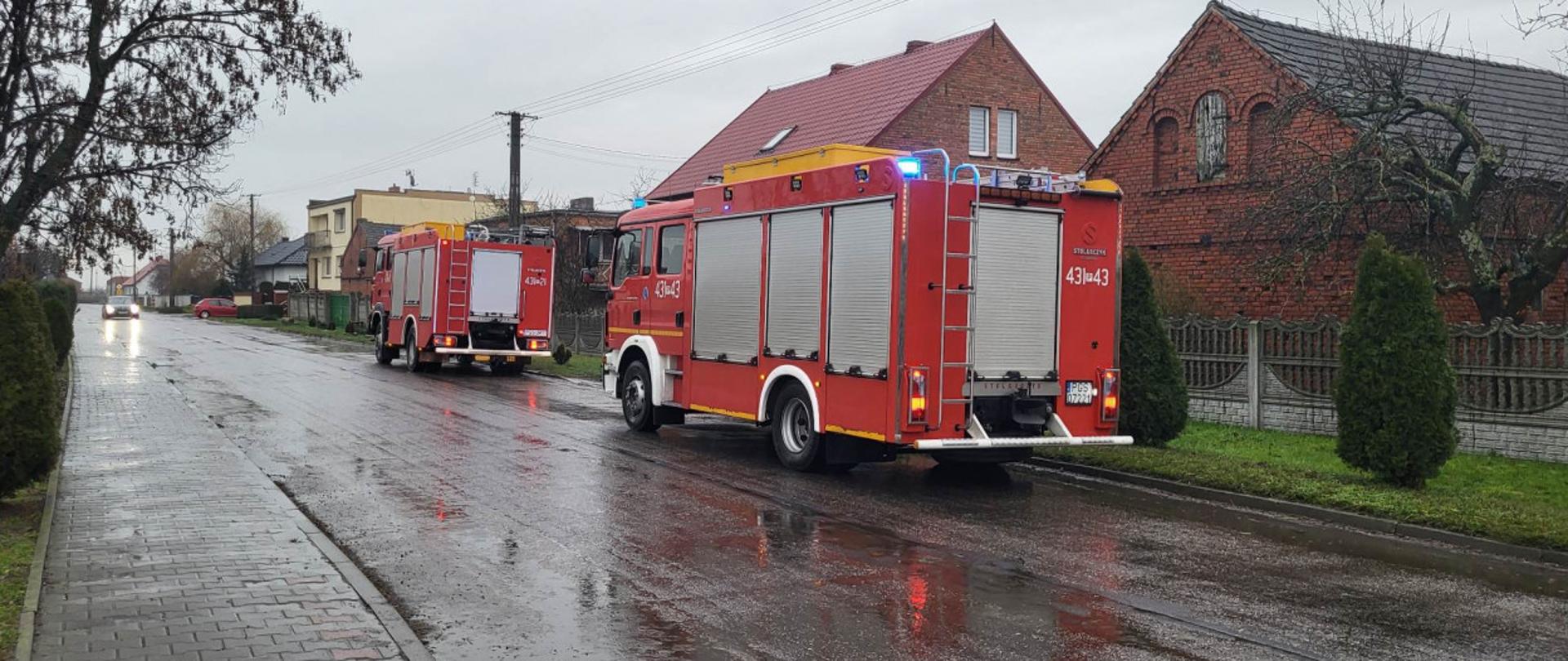 Dwa wozy strażackie stoją na drodze podczas interwencji.
