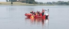 Strażacy na łodzi ćwiczą podejmowanie osoby poszkodowanej.