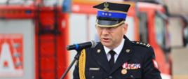 Podlaski komendant wojewódzki PSP - st. bryg. Janusz Kondrat uczestniczył w majowym święcie kolneńskich strażaków - stoi przy mównicy podczas przemówienia, pada deszcz