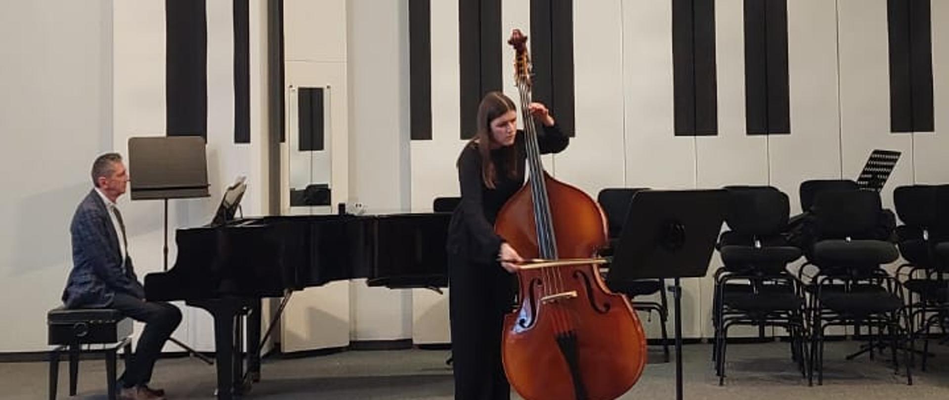 Dziewczyna gra na kontrabasie, mężczyzna akompaniuje jej na fortepianie.