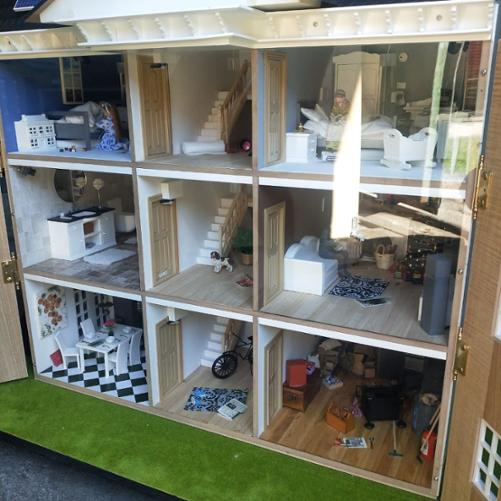 Makieta trzypiętrowego domu pokazuje wnętrza różnych pomieszczeń