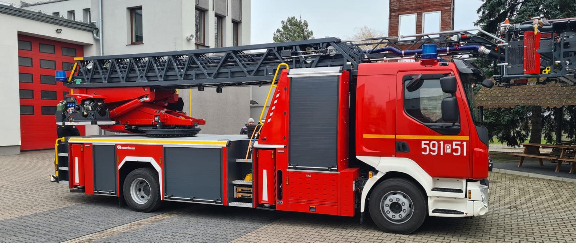 Samochód z drabiną mechaniczną na placu komendy, widok prawa strona