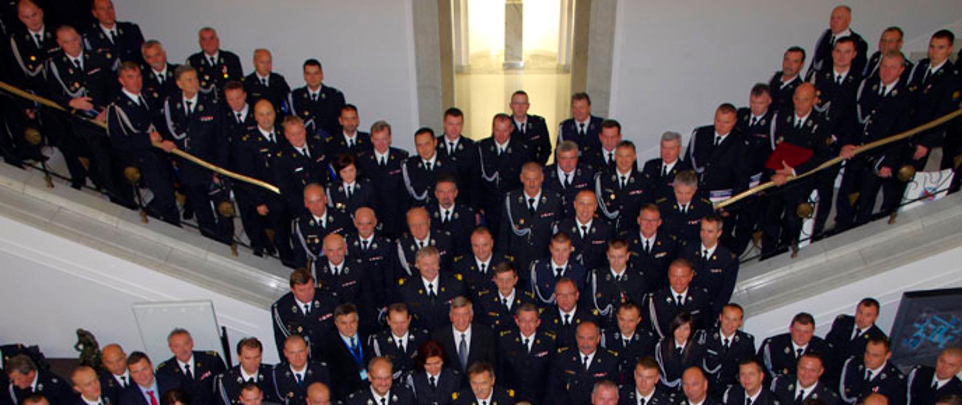 Zdjęcie grupowe strażaków ochotników w mundurach galowych na schodach w sejmie