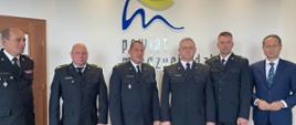 Na zdjęciu znajduje się 4 strażaków, którzy byli na misji w Grecji, obok Komendant Powiatowy PSP i Starosta Międzychodzki. W tle logo powiatu międzychodzkiego