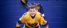 Zdjęcie przedstawia chłopca w stroku hokejowym.
